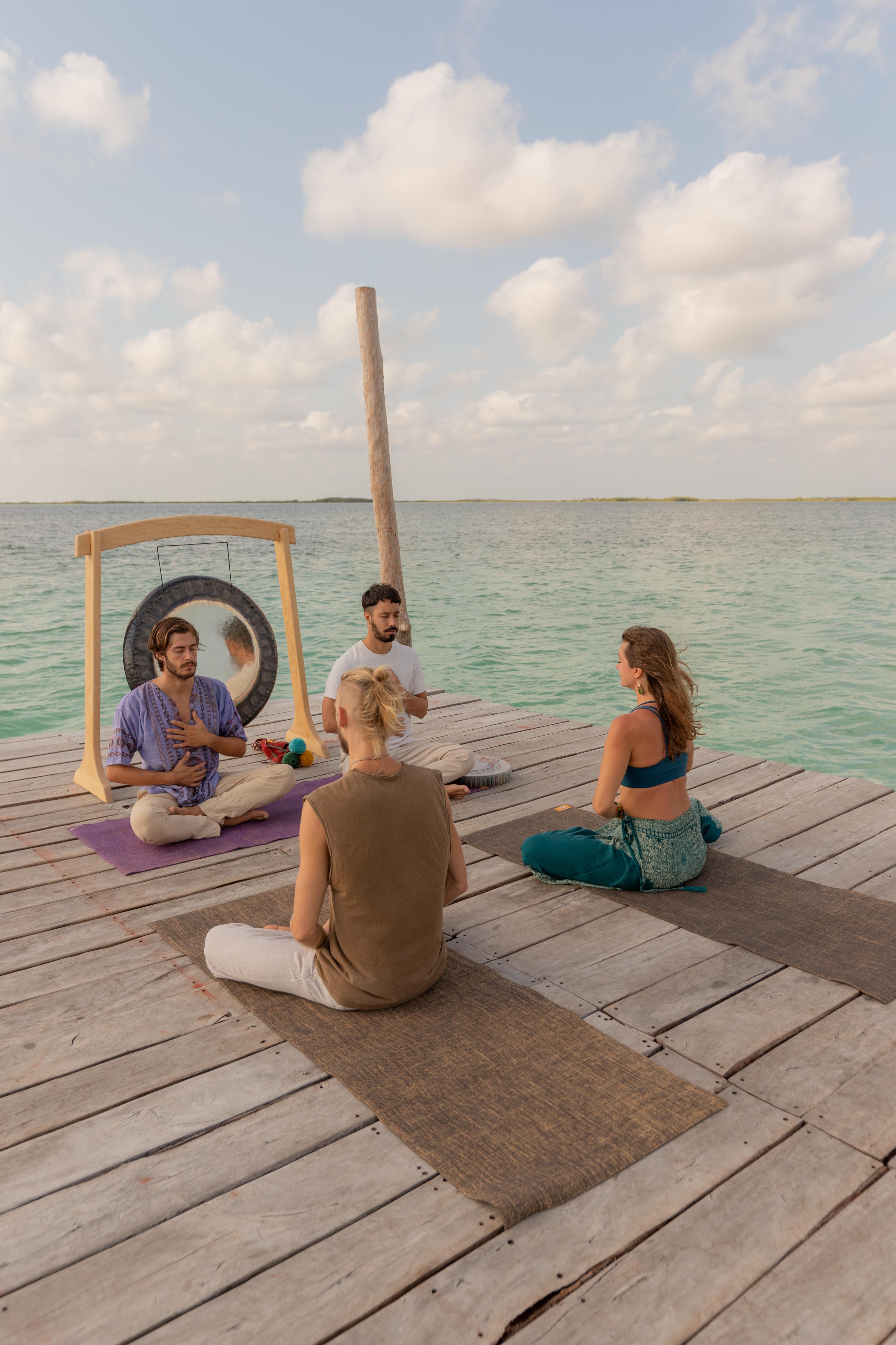 Sesión grupal con gong sobre el muelle de Bacalar al atardecer